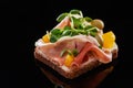 Close up of ham on prepared danish smorrebrod sandwich on black.