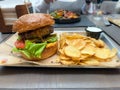 Close-up of a hamburger with lettuce and a side of potato chips, sitting on a plate