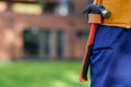 Close up of hammer hanging in tool belt on waist area of male builder in blue overalls