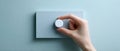 Close-up of hand adjusting modern white rotary dimmer switch on textured light blue wall panel in minimalistic setting Royalty Free Stock Photo