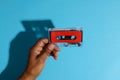 Close up of hand of african american man holding red cassette tape over blue background Royalty Free Stock Photo