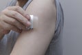 A close-up of a hand applying a nicotine patch to the upper arm. Represents Nicotine Replacement Therapy (NRT) Royalty Free Stock Photo