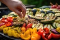 close-up of hand arranging grilled veggies on a platter