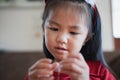 Close up hand of asian child girl is threading beads onto a string