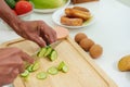 Close-up hand of Asian man using a knife to thinly slice cucumbers. It's a cutting board that sits on the kitchen Royalty Free Stock Photo