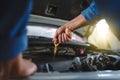 Close up of the hand of an asian mechanic. Auto mechanic is checking the engine oil in a vehicle at the garage. Maintenance