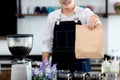 Close up hand. Asian young smiling Cashier holding paper bags while attractive brunette barista making coffee in coffee cafe. Royalty Free Stock Photo