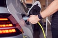 Close Up Of Hand Attaching Power Cable To Environmentally Friendly Zero Emission Electric Car