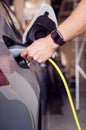 Close Up Of Hand Attaching Power Cable To Environmentally Friendly Zero Emission Electric Car