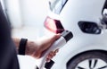 Close Up Of Hand Attaching Power Cable To Environmentally Friendly Zero Emission Electric Car