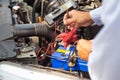 Close up hand of auto mechanic using measuring equipment tool checking car battery.