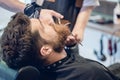 Close-up of the hand of a barber trimming the beard of a customer