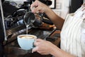 Close-up hand of barista making latte or cappucino coffee in coffee shop. Cafe restaurant service, food and drink industry