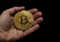 Hand holding a golden Bitcoin coin on a black background Royalty Free Stock Photo