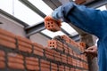 Close up hand of Bricklayer worker installing brick masonry on exterior wall on construction site Royalty Free Stock Photo