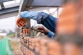 Close up hand of Bricklayer worker installing brick masonry on exterior wall with trowel putty knife on construction site