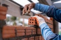 Close up hand of Bricklayer worker installing brick masonry on exterior wall with trowel putty knife on construction site