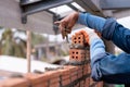 Close up hand of Bricklayer worker installing brick masonry on exterior wall with trowel putty knife on construction site