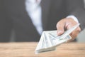 Close up hand of businessman holding money dollar bills on wooden table. Using as concept of corruption , Royalty Free Stock Photo