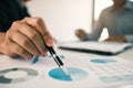 Close up hand of a businessman holding a pen pointing to graph of financial statements or company profits and analyzing on the Royalty Free Stock Photo