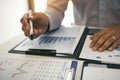 Close up hand of a businessman holding a pen pointing to graph of financial statements or company profits and analyzing on the Royalty Free Stock Photo