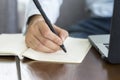 Close up hand of Businessman planning writing note and working with laptop computer on desk. Writing something idea on notebook or Royalty Free Stock Photo