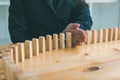 Close up hand businessman stopping wooden block from falling in the line of domino with risk concept Royalty Free Stock Photo