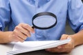 Close up hand of businessperson looking at documents through magnifying glass. Royalty Free Stock Photo