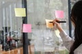 Close up hand businesswoman writing sticky notes on glass wall in office Royalty Free Stock Photo