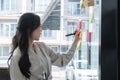 Close up hand businesswoman writing sticky notes on glass wall in office Royalty Free Stock Photo