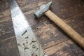 Close up of hand carpentry tools and hardware. Handsaw with rust, retro hammer and screws on wooden vintage background. Royalty Free Stock Photo