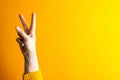 Close up of hand of caucasian woman making peace sign with copy space on yellow to orange background Royalty Free Stock Photo