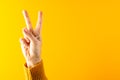 Close up of hand of caucasian woman making peace sign with copy space on yellow to orange background Royalty Free Stock Photo