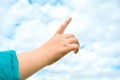 Child hand with exposed index finger raised up over blue sky and clouds. Gesture Royalty Free Stock Photo