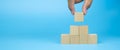 Close-up hand choose cube wooden block toy stack in pyramid without graphics Royalty Free Stock Photo