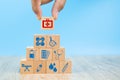 Close-up hand choose Health care and medical symbols on wooden blocks toy stacked in pyramid shape.