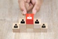 Close up hand choosing people icons with a light bulb on cube wooden toy blocks stack in pyramid shape Royalty Free Stock Photo