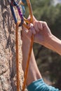 Hand of a climber passing the rope through a quickdraw while climbing route. Royalty Free Stock Photo