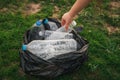 Close up hand collects plastic bottle in a park. A volunteer cleaning garbage.