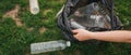 Close up hand collects plastic bottle in a park. A volunteer cleaning garbage.