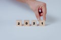 Close up of hand completing the year 2021 with symbolic drops of blood on wooden cubes, concept