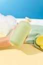 Close-up of a hand covered in white foam holding an unlabeled bottle of shower gel, next to a towel, bath sponge and sponge. Royalty Free Stock Photo