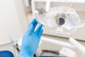 Close-up hand of dentist in the glove adjusts the lamp. . Office where dentist conducts inspection and concludes.