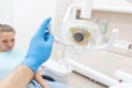 Close-up hand of dentist in the glove adjusts the lamp. The patient in blue chair at the background. Office where Royalty Free Stock Photo