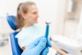 Close-up hand of dentist in the glove holds dental high speed turbine. The patient in blue chair at the background