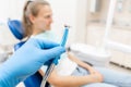 Close-up hand of dentist in the glove holds dental high speed turbine. The patient in blue chair at the background