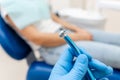 Close-up hand of dentist in the glove holds dental high speed turbine. The patient in blue chair at the background Royalty Free Stock Photo