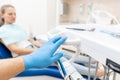 Close-up hand of dentist in the glove holds dental high speed turbine. The patient in blue chair at the background Royalty Free Stock Photo