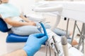 Close-up hand of dentist in the glove holds dental high speed turbine. The patient in blue chair at the background Royalty Free Stock Photo