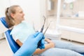 Close-up hand of dentist in the glove holds tool probe and mirror. The patient in the dental chair at the background